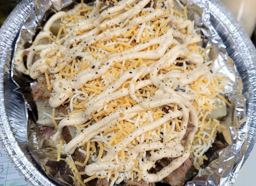 The Porker spud with shredded garlic pork, cheese, and garlic aioli